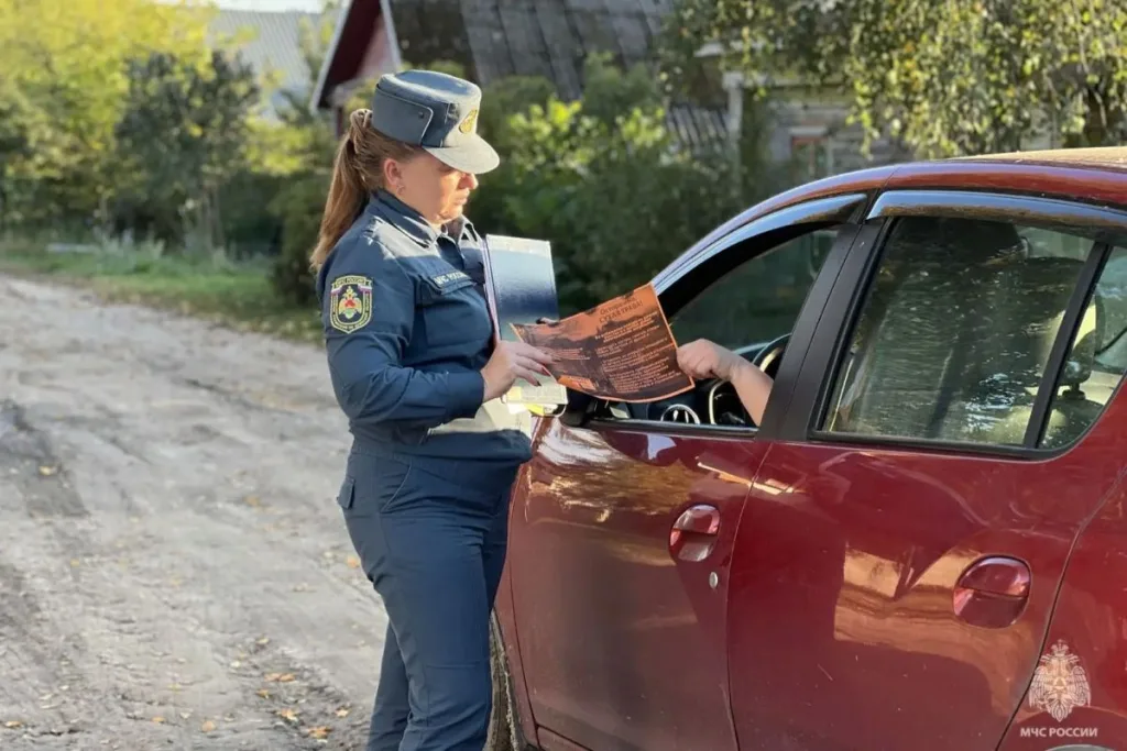 Сотрудник МЧС раздает информационную листовку жителю