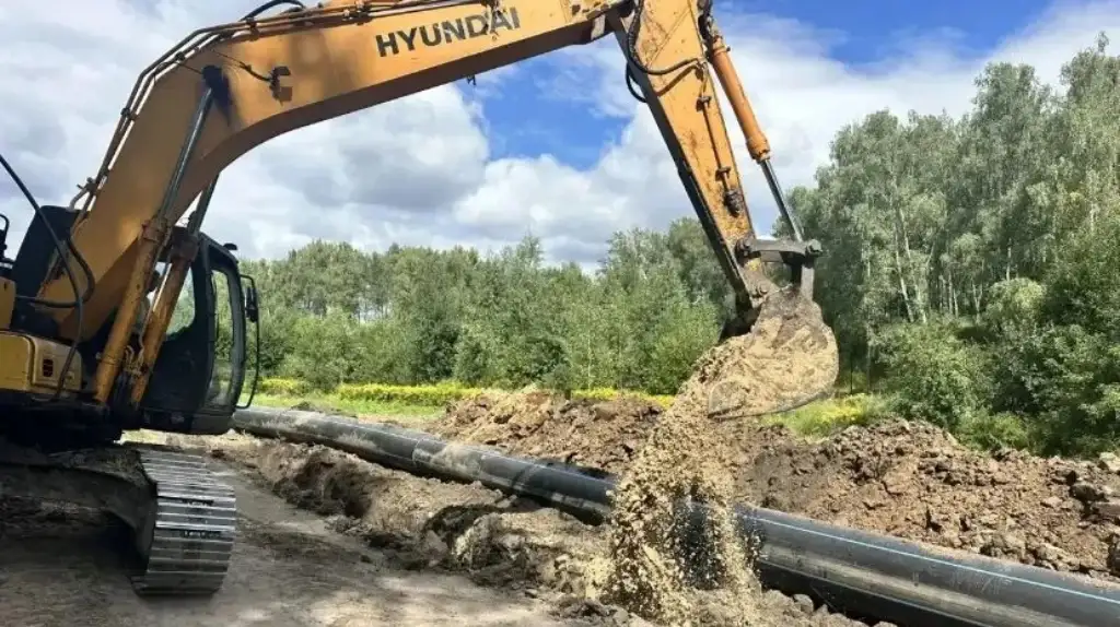 Экскаватор укладывает новый водопровод