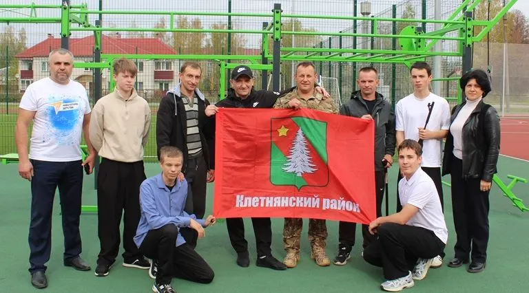 Группа людей с флагом района на спортплощадке