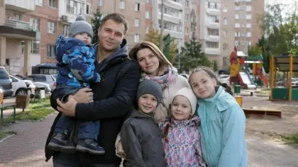 Семья с детьми во дворе многоэтажного дома