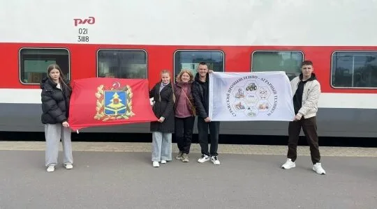 Участники слёта у поезда с флагом региона